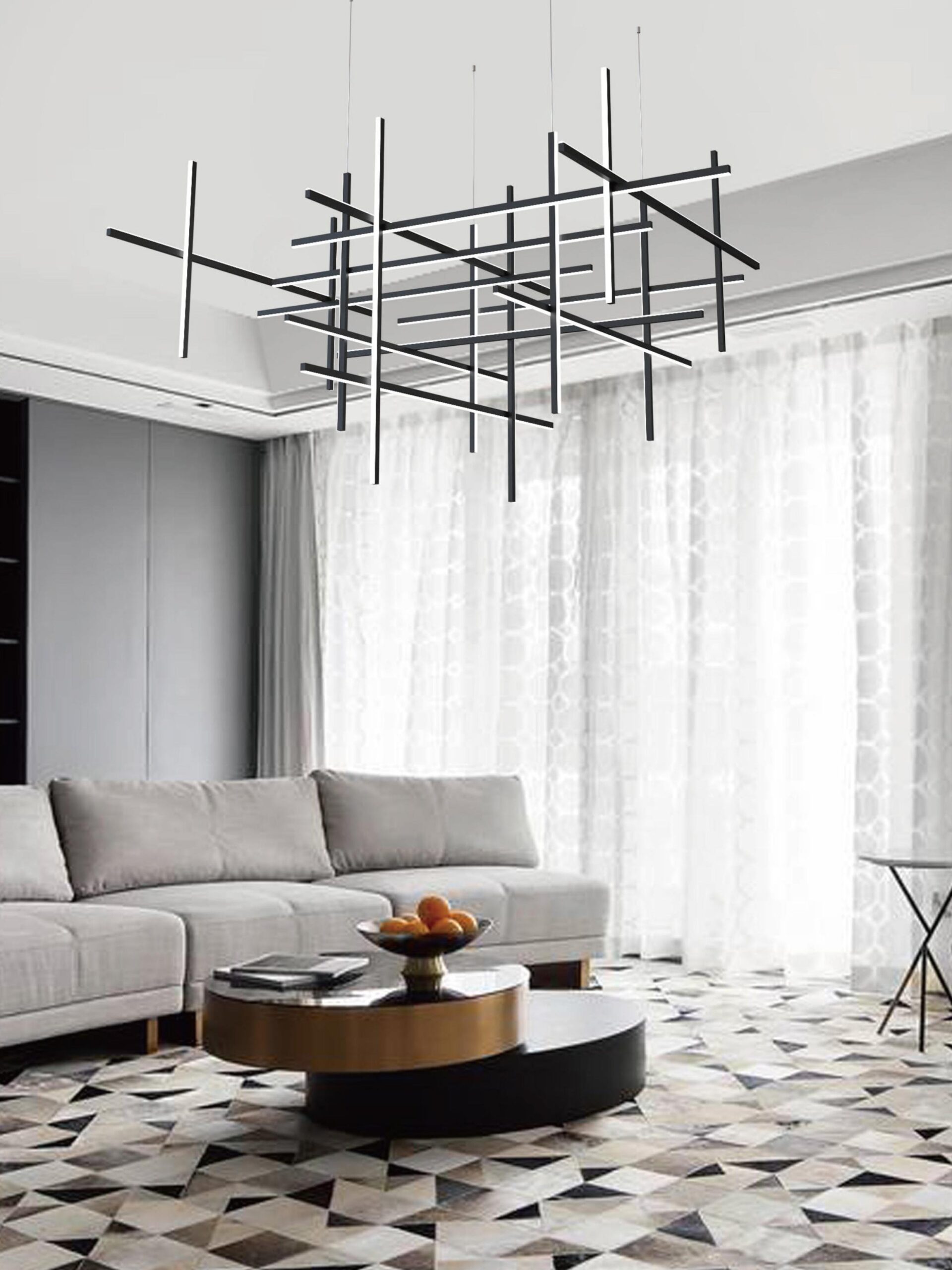 Architectural black tubular pendant light forming a striking geometric centerpiece in a bright, contemporary living room with a grey sectional and patterned rug.