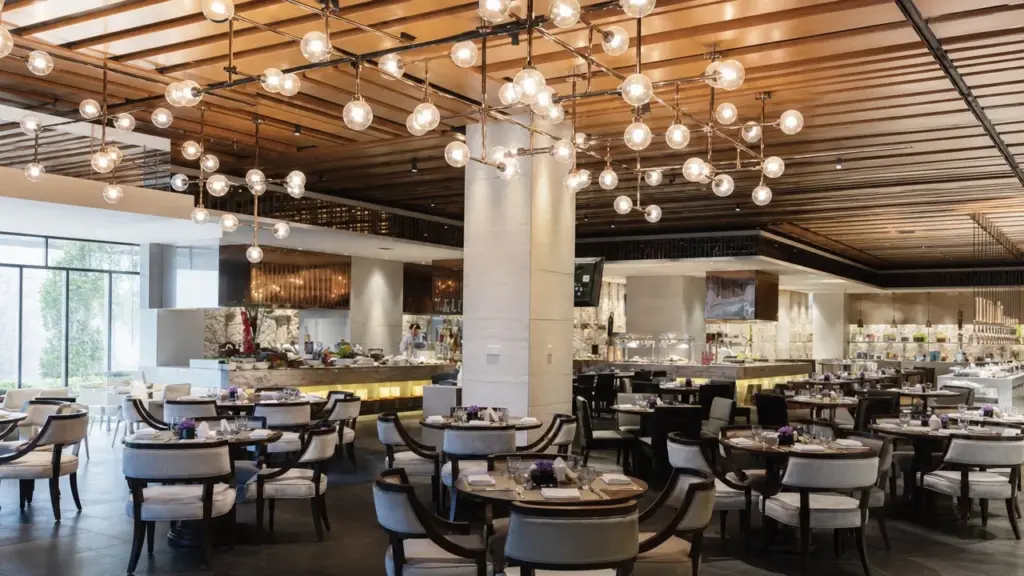 Glaskugelleuchten an verzweigten Metallgestellen über Restauranttischen unter einer Holzdecke.