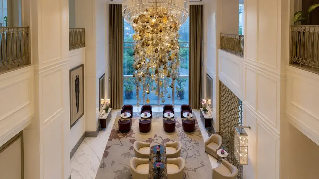 Customer-provided image of a tall decorative chandelier suspended in a double-height interior with upper-level balustrades